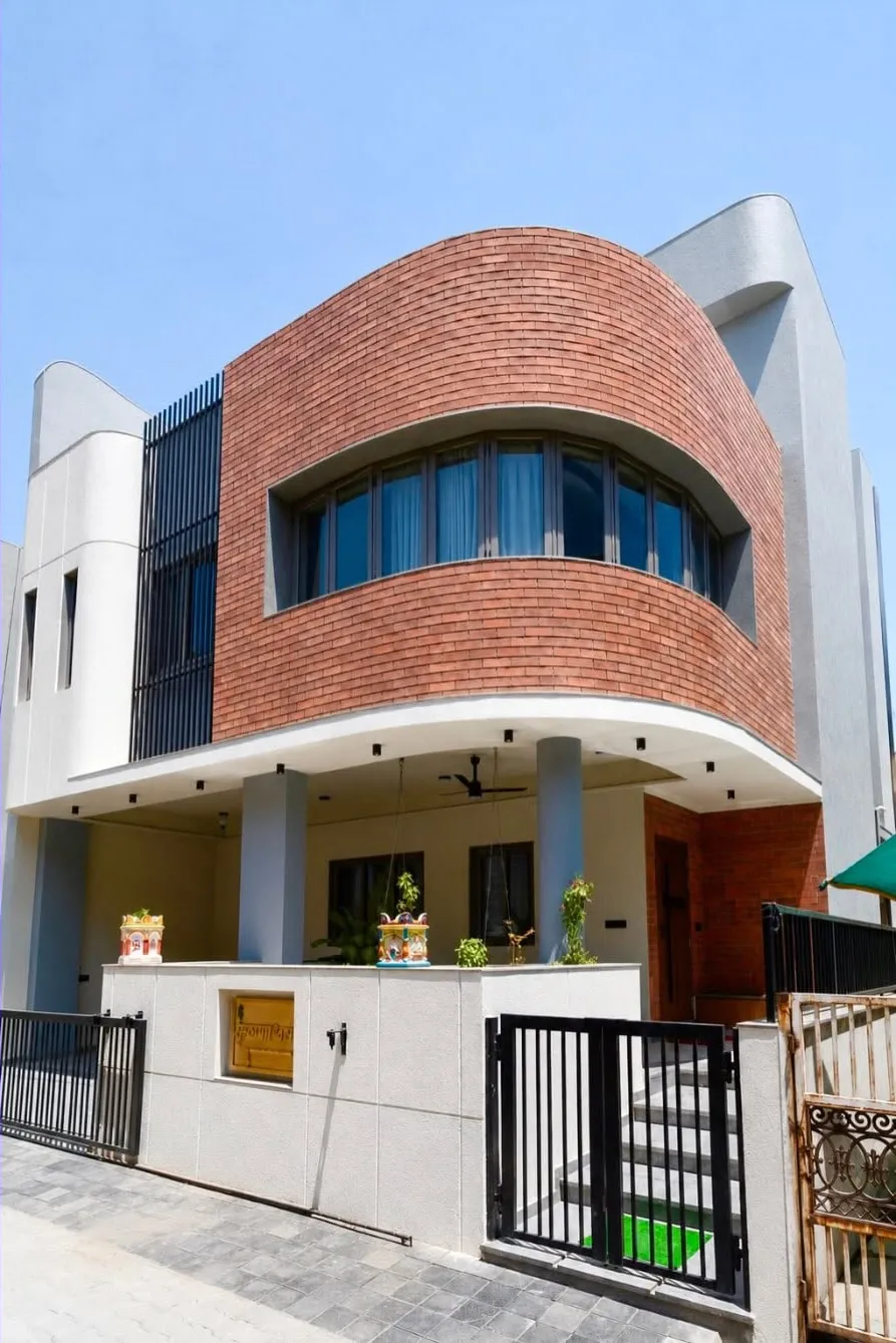 Three-quarter view of Krishnashray emphasising the sweeping curve of the brick upper floor cantilevered over the entrance porch.